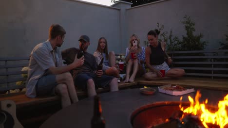 a group of friends are sitting near a fire, chatting and having a happy time while relaxing in the courtyard of a country house