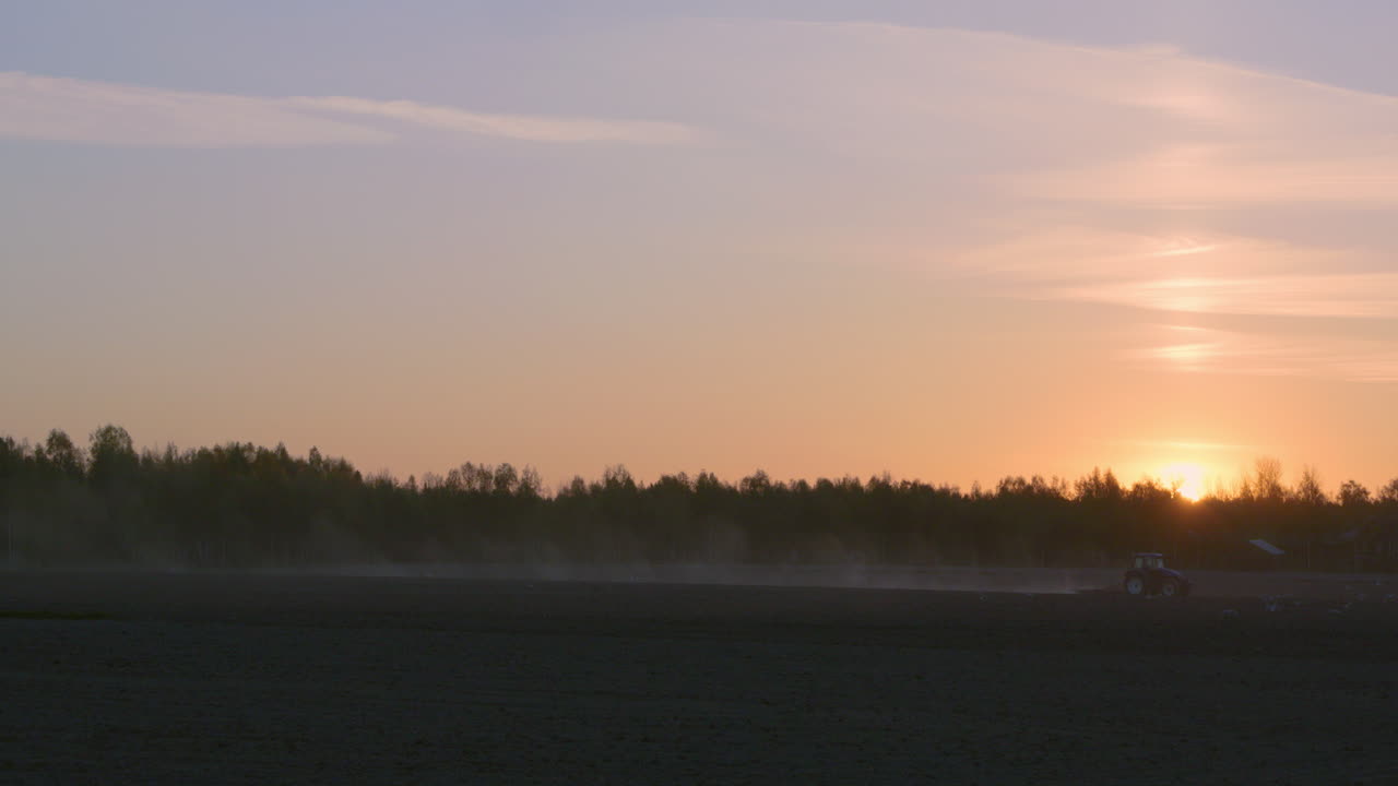 Wide shot of Tractor working late at night at sunset, copy space room for text