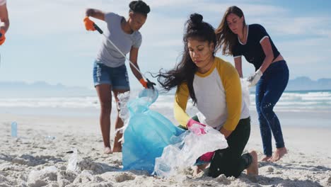 grupo diverso de amigas poniendo basura en bolsas de basura en la playa