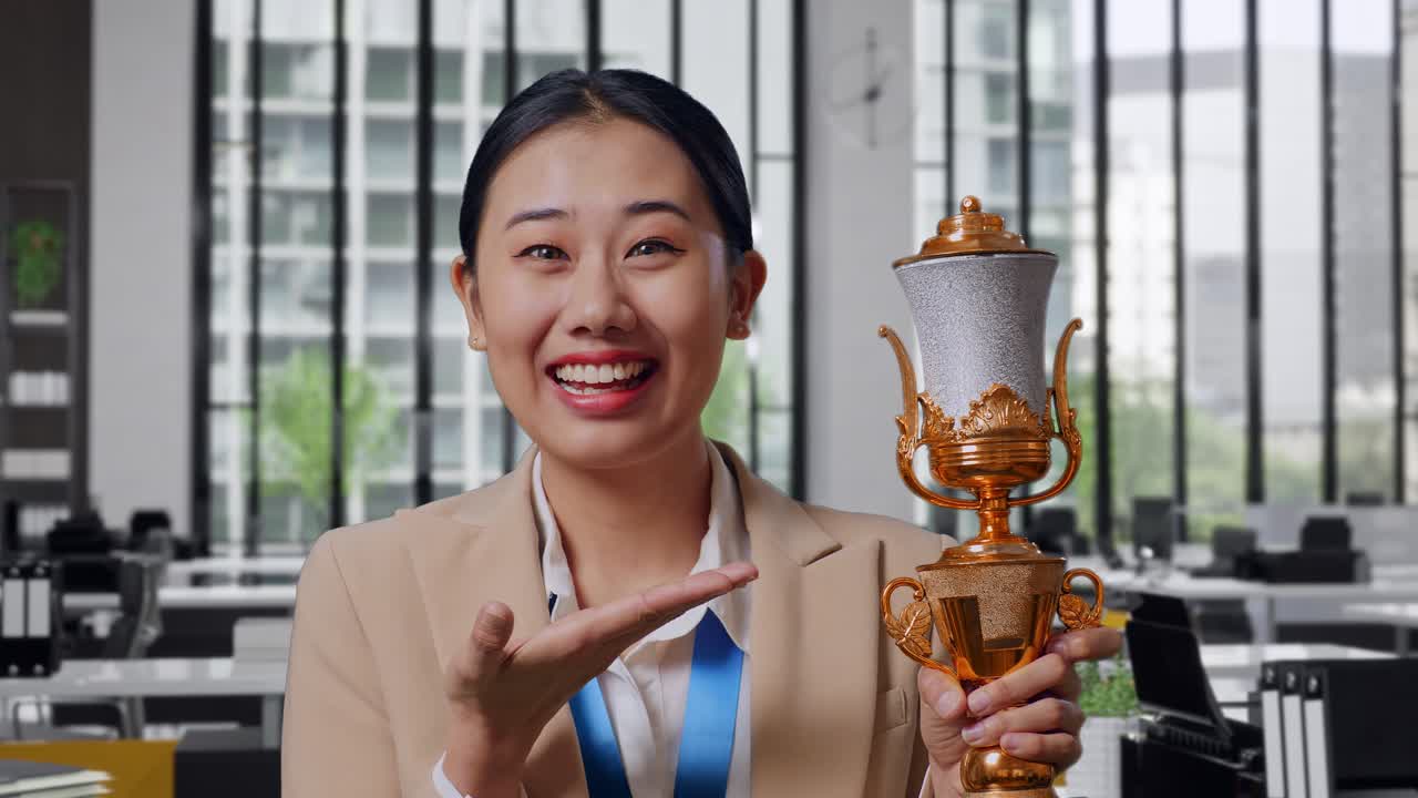 Woman Celebrating Achievement with Trophy in Modern Office