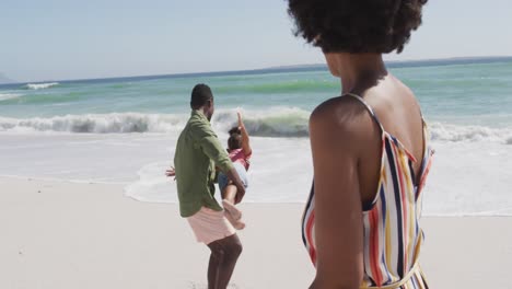 Lächelndes-Afroamerikanisches-Paar-Mit-Tochter,-Die-Am-Sonnigen-Strand-Spielt