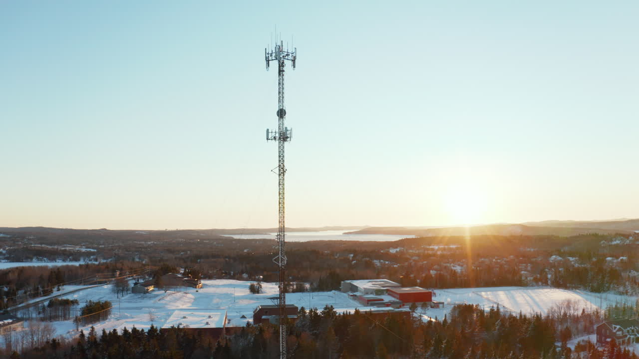 vista aérea de una torre de telefonía celular en un barrio suburbano nevado al atardecer