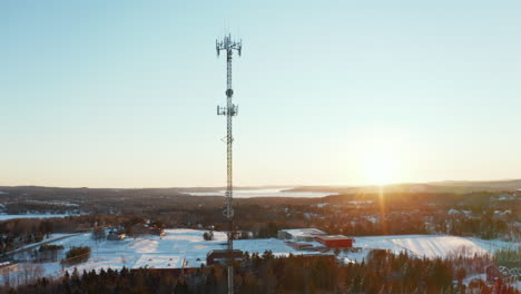 Vista-Aérea-De-Una-Torre-De-Telefonía-Celular-En-Un-Barrio-Suburbano-Nevado-Al-Atardecer