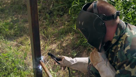 soldador con guantes utiliza una máquina herramienta para fijar la carcasa de la valla