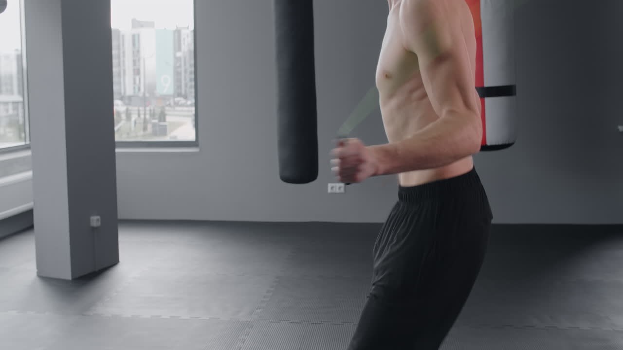 Man Jumping Rope in Gym with Boxing Bags