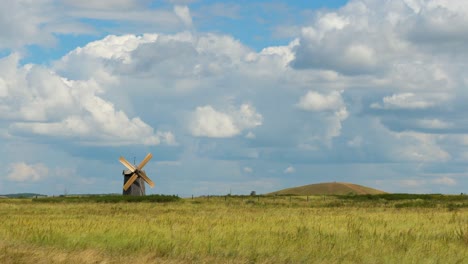 wooden windmill in a field under a cloudy sky