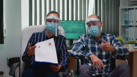 man in wheelchair and coworker with visor having videomeeting