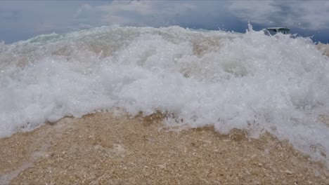 ola chocando en la playa de arena ángulo bajo, cámara lenta