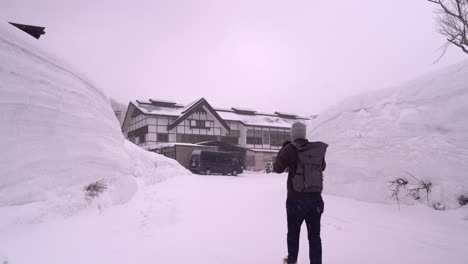 hombre caminando hacia un edificio antiguo junto a altos muros de nieve