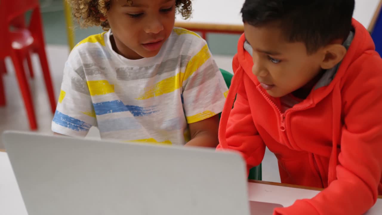 vista frontal de escolares de raza mixta estudiando en una computadora portátil en el aula 4k