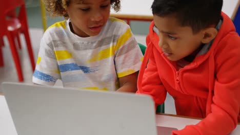 Front-view-of-Mixed-race-schoolboys-studying-on-laptop-in-the-classroom-4k