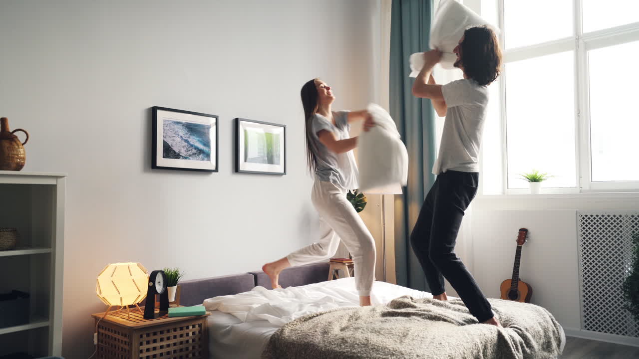 Couple having a pillow fight in bedroom