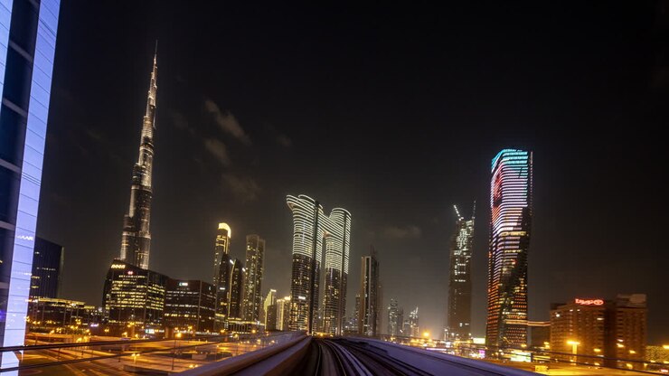 Vue nocturne de la ligne d'horizon de la ville de Dubaï depuis un train de métro aérien