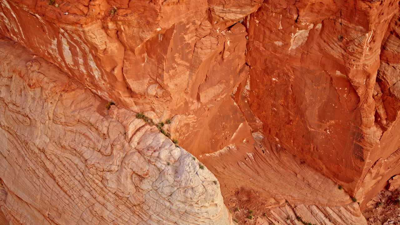 Drone glides above captivating geological forms etched into the red canyon cliffs.