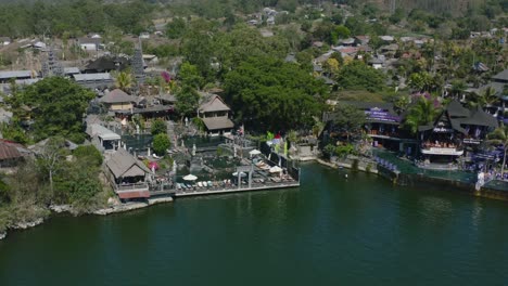 volcanic-hot-springs-near-a-lake-in-bali-with-large-Indonesian-flag-waving,-aerial