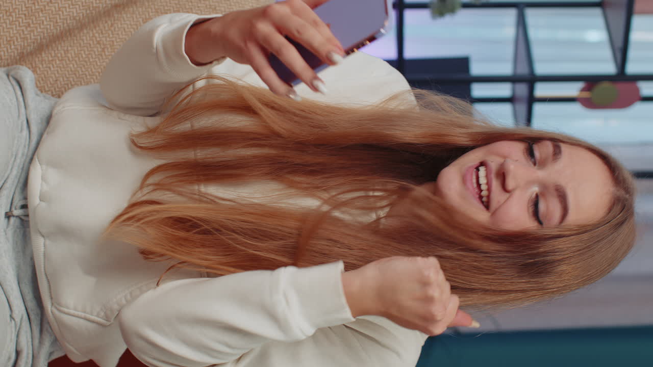 Feliz chica encantadora en el sofá de casa usar teléfono inteligente escribir navegación decir wow sí descubrió gran gran ganancia