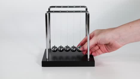 hand sets newton's cradle in motion