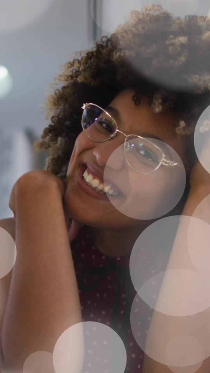 Animation of spots over african american woman drinking wine and having video call