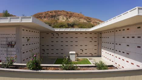 Low-aerial-reverse-pullback-shot-of-a-stone-mausoleum-with-a-flower-garden-at-a-mortuary-in-California