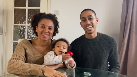 Young-Parents-with-Small-Niño-On-Video-Call-Listening-to-a-Friends-Story-Directly-into-Camera