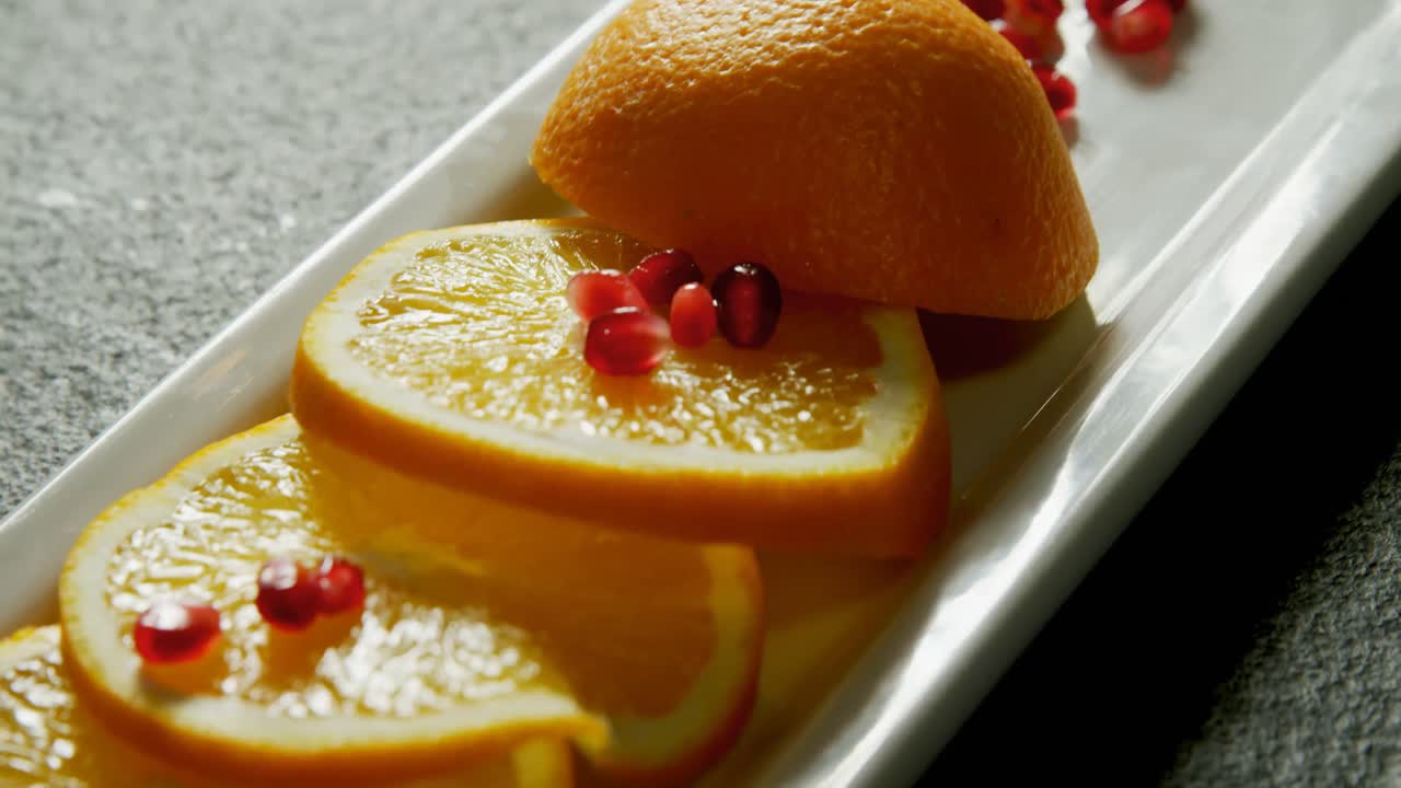 Slice of orange with pomegranate seeds in tray on grey background 4K 4k