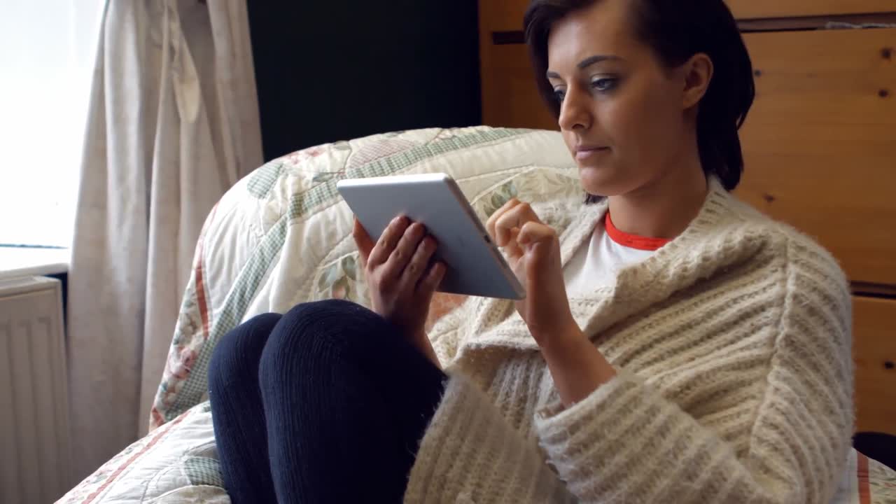 Beautiful woman using digital tablet in bedroom