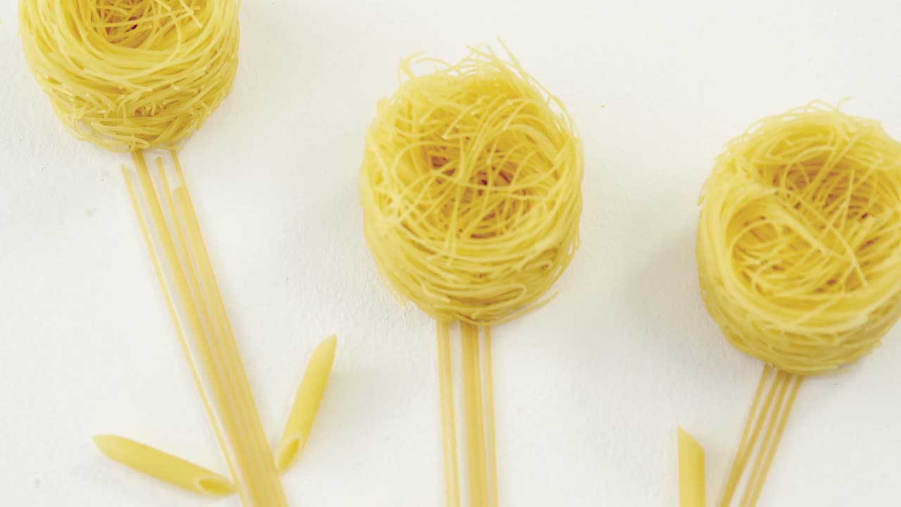 espaguetis dispuestos en forma de flor sobre un fondo blanco