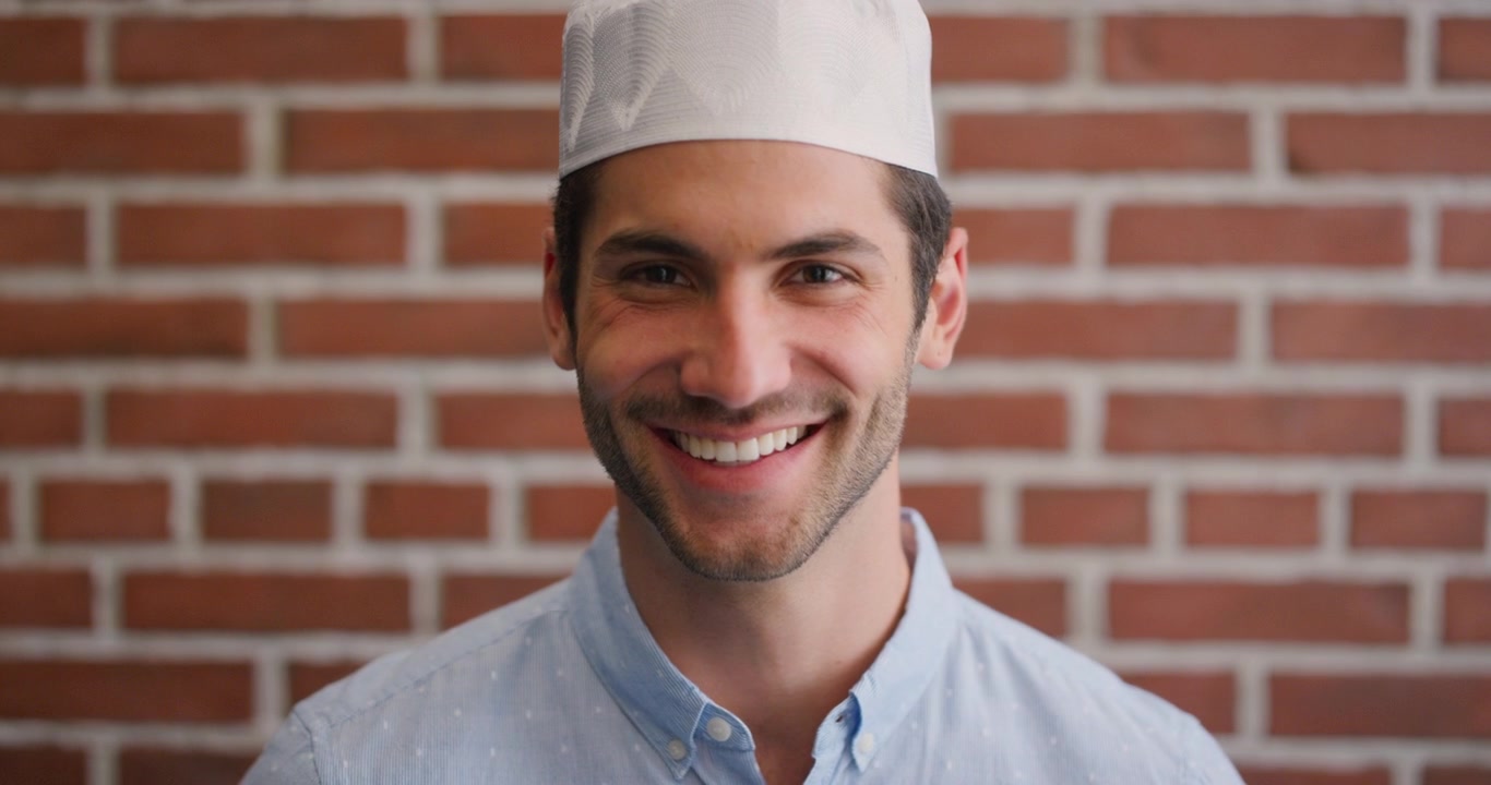 Giovane uomo sorridente che indossa un tradizionale berretto kufi