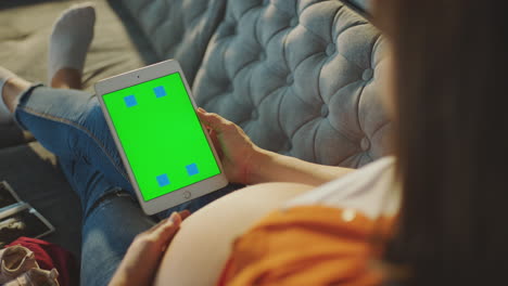 pregnant woman using a tablet with a green screen