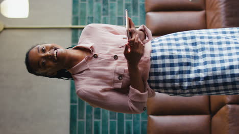 Vertical-Video-Portrait-Of-Smiling-Female-Owner-Or-Staff--With-Digital-Tablet-Working-In-Coffee-Shop