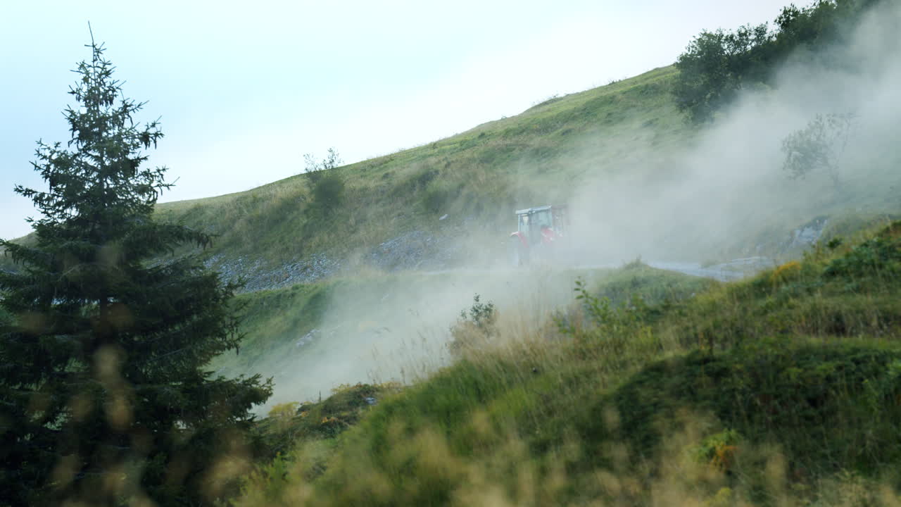 un tractor rojo camina por un camino difícil en las montañas rodeado de nubes
