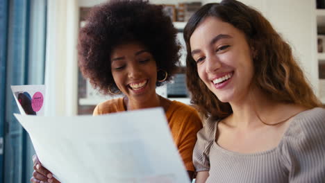 Two-Young-Female-Business-Colleagues-With-Documents-Meeting-Together-In-Office