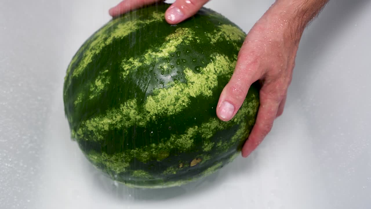 한 남자가 은 수박을 손으로 고 있습니다.
