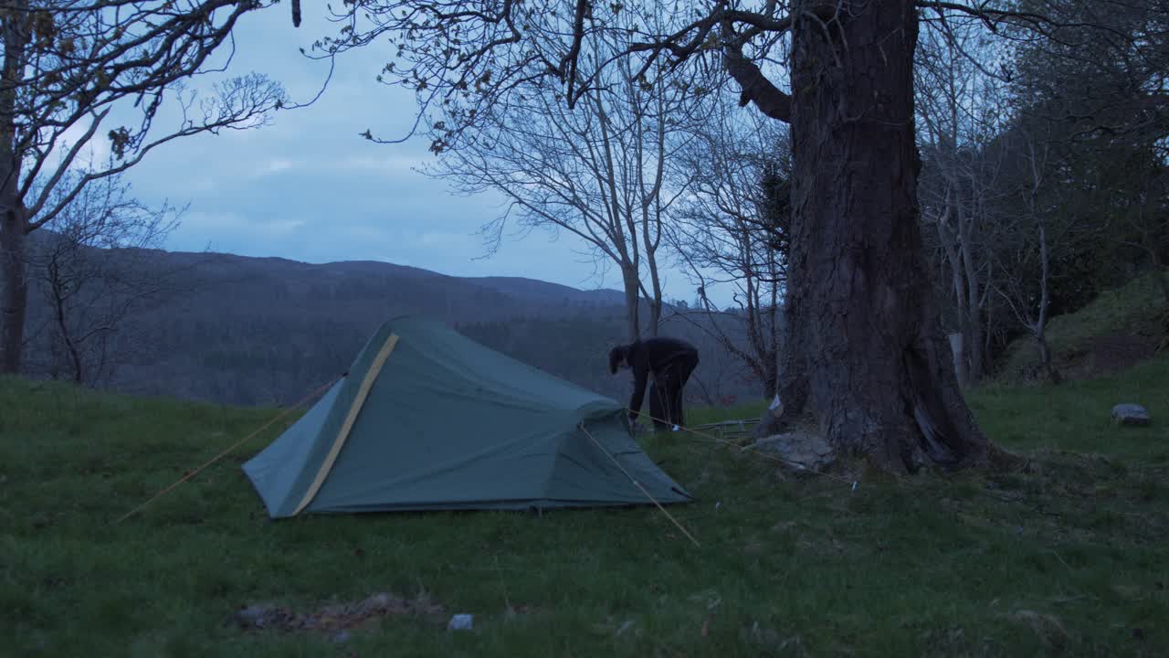 캠핑을 하는 청년은 야외 화재를 위해 돌을 운반한다