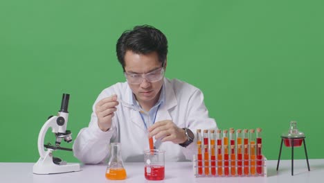 asian man scientist making experiment with test tube and screaming goal celebrating while working on the table with microscope in the green screen background laboratory