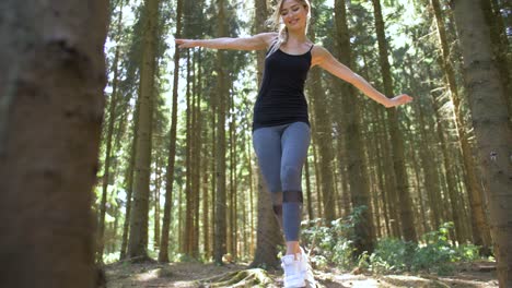 Woman-smiling-as-she-walks-across-a-log