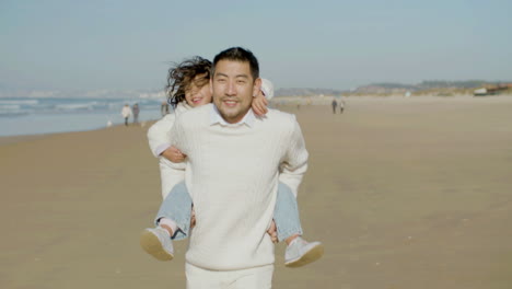 그의 귀여운 작은 딸을 피기백 태워주는 행복한 일본 아빠의 전면 모습