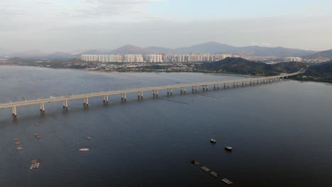 puente de la bahía de hong kong shenzhen con edificios tin shui wai en el horizonte y piscinas de cultivo de peces y ostras, vista aérea