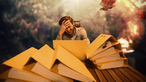 animation of leaves falling over nervous caucasian man working on laptop with documents on desk