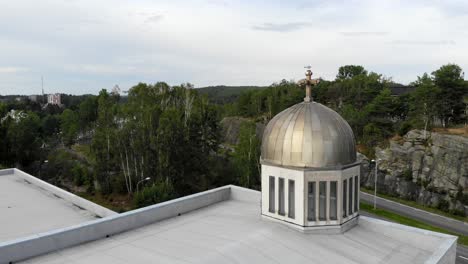 vista aérea alrededor de un pájaro en una cruz de cúpula de iglesia, día nublado, en suecia - seguimiento, disparo de drones