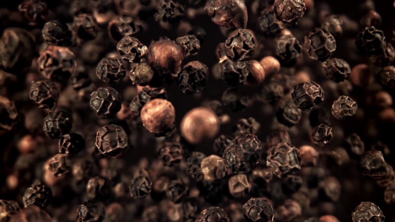 Svarte pepperkorn faller i super sakte film med detaljert tekstur