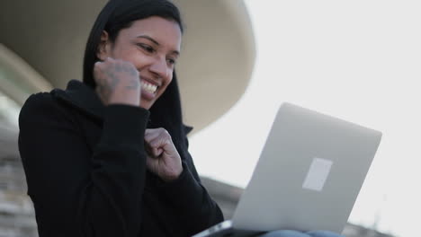 Rejoicing-young-hindu-woman-with-laptop-sitting-outdoor