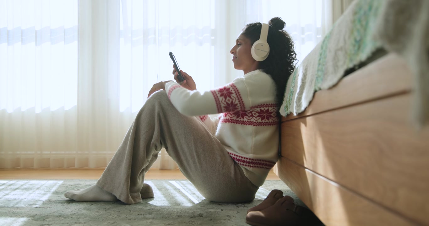 Donna con le cuffie che nota il telefono, lo prende, lo controlla, fissando la luce della finestra in camera da letto
