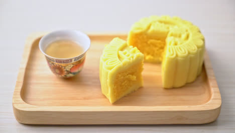 Chinese-moon-cake-custard-flavour-with-tea-on-wood-plate