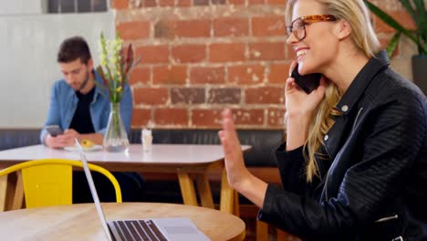 Woman-talking-on-mobile-phone-while-using-laptop-4k