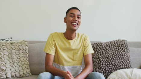 happy mixed race man sitting on sofa laughing and talking