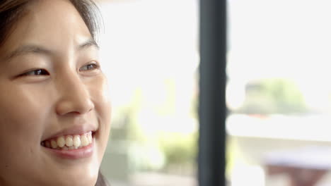 smiling asian woman enjoying bright interior space, happiness and positivity, copy space, at office