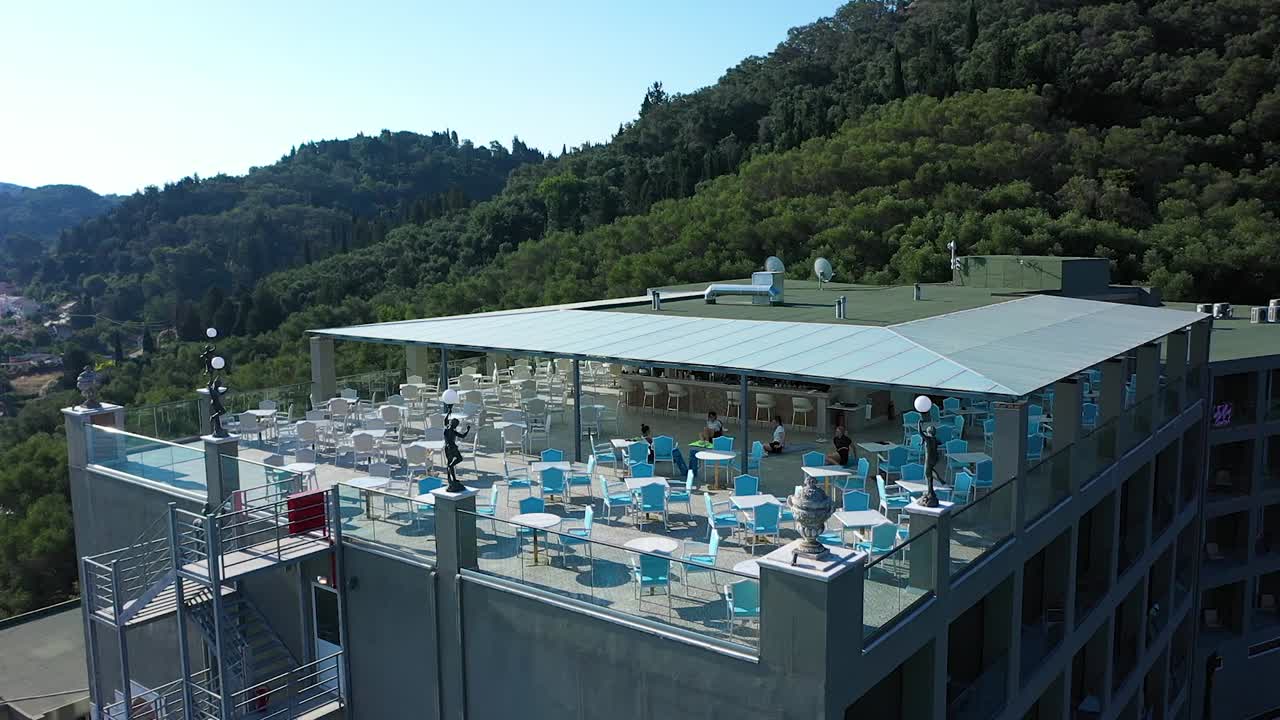 Tracking shot view terrace Mythos Palace Hotel, Corfu, on sea and coastline,