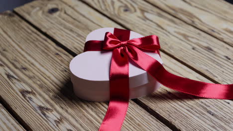 heart-shaped gift box with red ribbon on wooden table