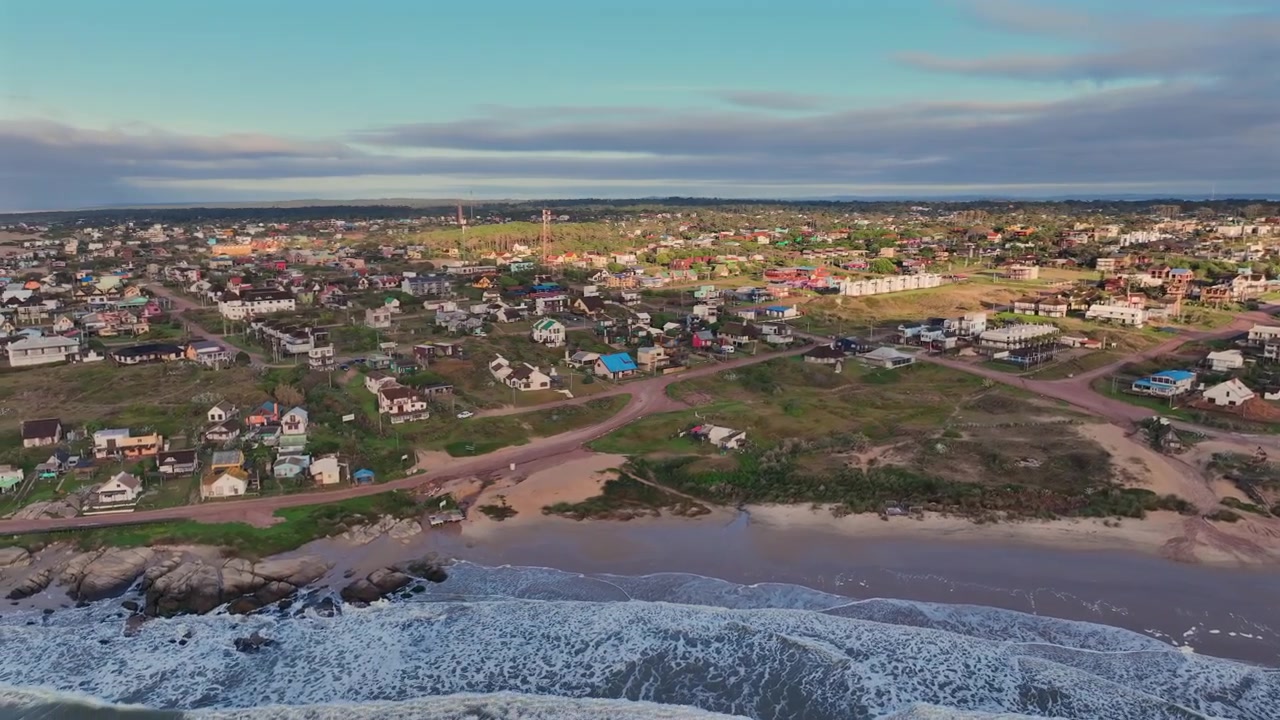 Thị trấn ven biển Punta del Diablo nhìn từ trên cao, tiết lộ những ngôi nhà ven biển, bãi biển cát, bờ biển đá và những con đường dân cư nội địa gần đại dương.